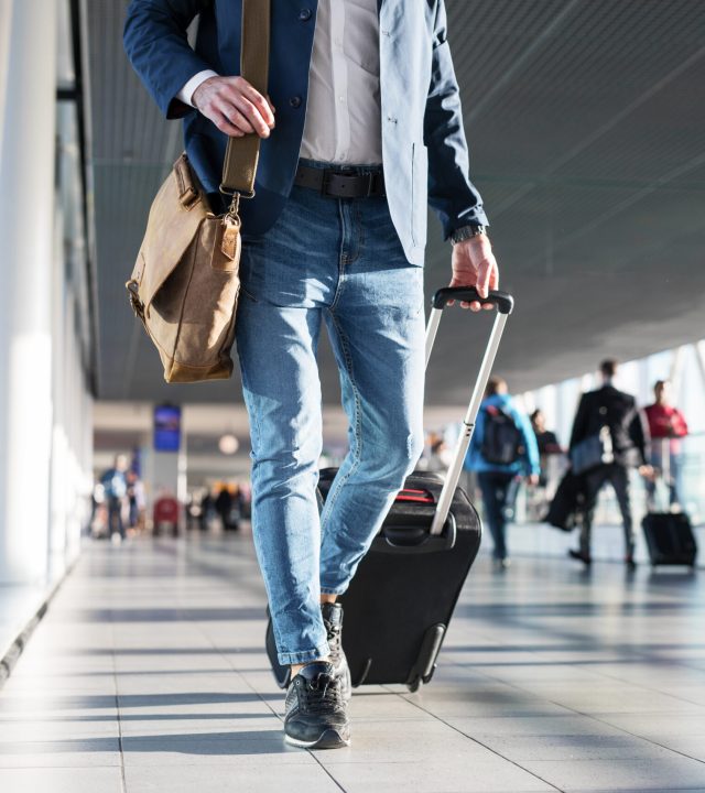 Man,With,Shoulder,Bag,And,Hand,Luggage,Walking,In,Airport